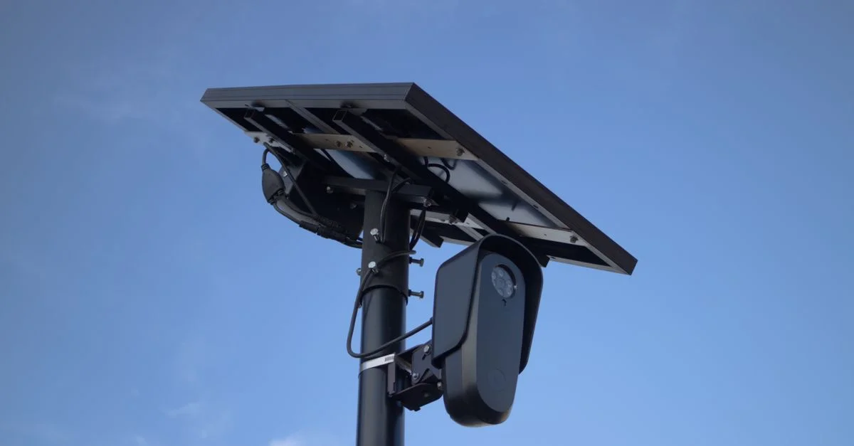 Caméra de surveillance alimentée par énergie solaire avec un fond de ciel bleu clair, mettant en avant la technologie moderne.