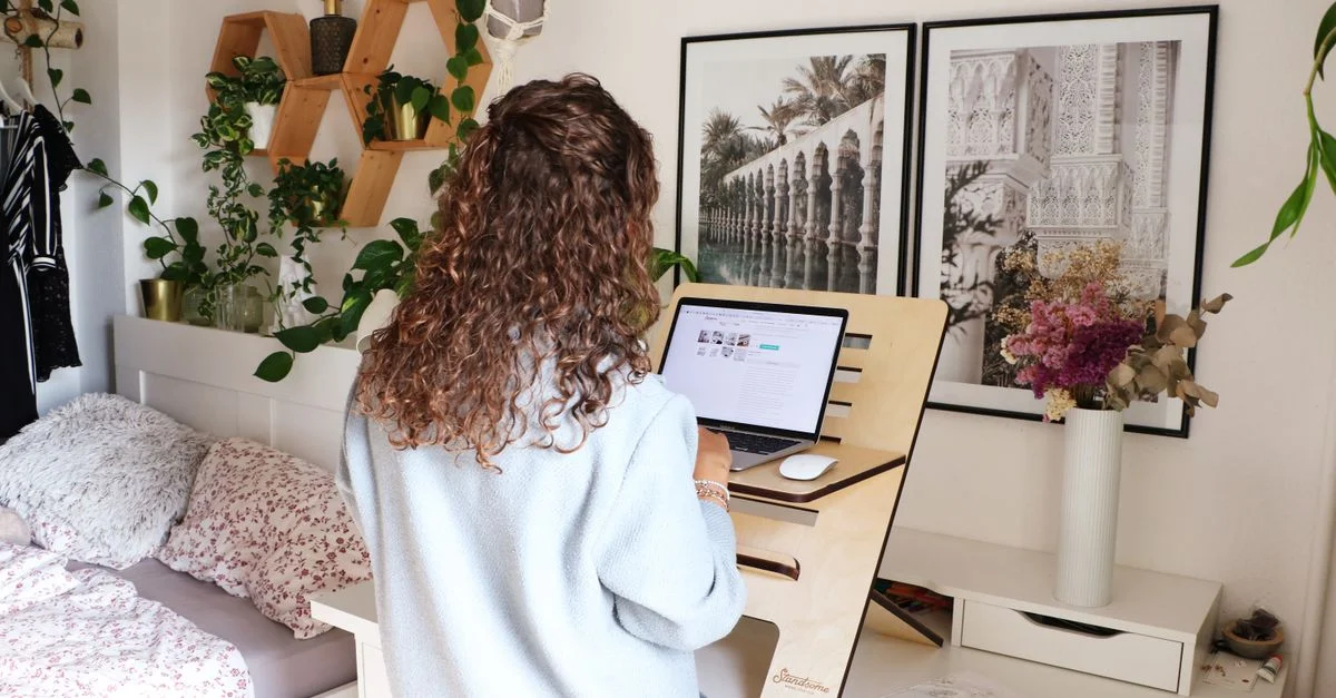 Mujer usando un laptop en un escritorio de casa con decoración y laptop.