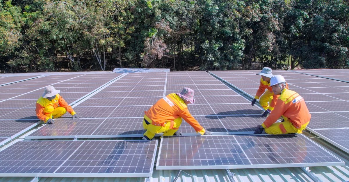 Equipo de trabajadores instalando paneles solares en un día soleado, promoviendo energía renovable y sostenibilidad.