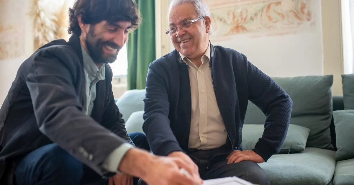 Un asesor y un cliente mayor discutiendo documentos durante una sesión de consultoría en interiores.